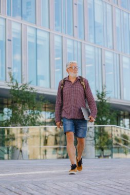 Gömlekli ve dizüstü bilgisayarlı kıdemli bir işadamı büyük bir şirkette kariyer yapıyor.