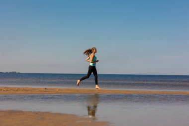Güzel ve atletik Avrupalı bir kız köpeğiyle doğada spor yapıyor. Zindelik ve yoga temiz havada. 