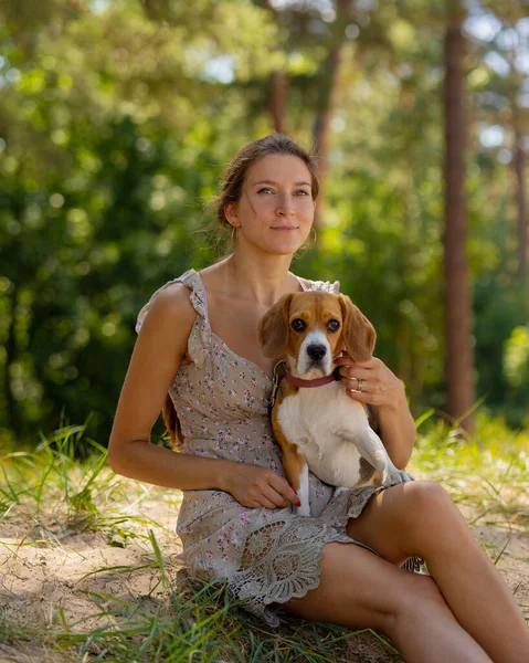 Una hermosa mujer europea pasea en la naturaleza con su perro beagle. fitness y yoga y meditación al aire libre. — Foto de Stock