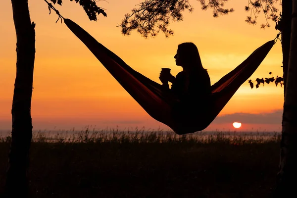 A European woman in a hammock in nature plays guitar and sings. a female travel blogger creates video content — Stock Photo, Image