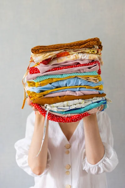 Avrupalı bir kadın çamaşırhanede yıkanmak ya da geri dönüşüm için elinde bir sürü renkli kıyafet tutar.