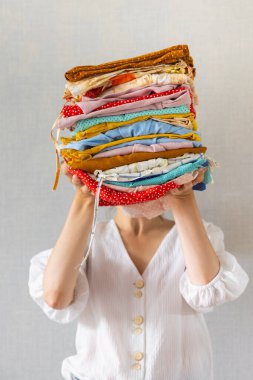 Avrupalı bir kadın çamaşırhanede yıkanmak ya da geri dönüşüm için elinde bir sürü renkli kıyafet tutar.
