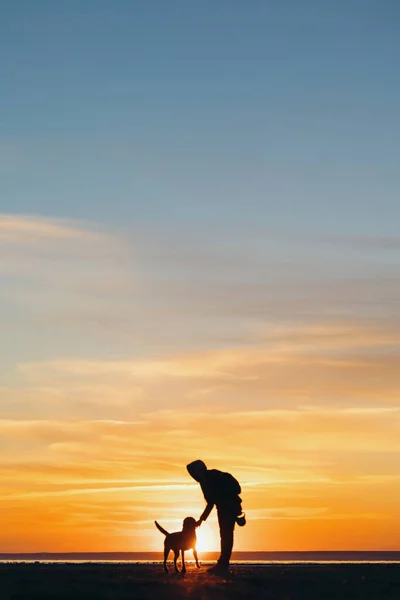 La silhouette di un uomo sullo sfondo di un tramonto su un lago o mare. una donna o un uomo sullo sfondo del sole al tramonto — Foto Stock