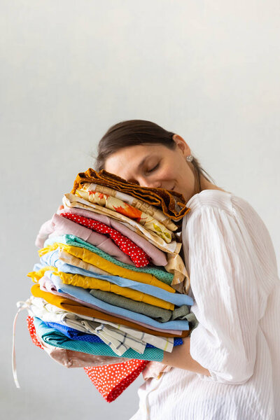 a European woman holds a lot of colored clothes in her hands for washing in the laundry or recycling