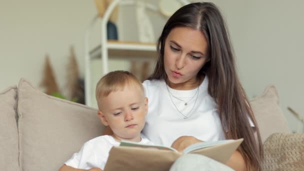 Ευρωπαϊκή οικογένεια μαμά και γιος παίζουν και να διαβάσετε ένα βιβλίο στο σπίτι. Η ανύπαντρη μητέρα μεγαλώνει ένα παιδί — Αρχείο Βίντεο