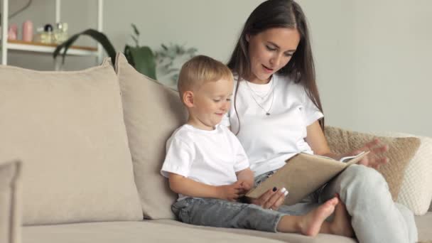 ครอบครัวยุโรปแม่และลูกชายเล่นและอ่านหนังสือที่บ้าน แม่คนเดียวนําเด็กมา — วีดีโอสต็อก