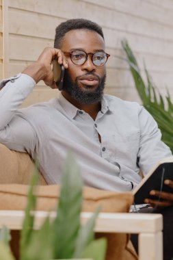 Ofiste çalışan ya da telefonda konuşan ve not defterine not alan Afro-Amerikan. 