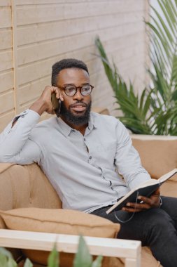 Ofiste çalışan ya da telefonda konuşan ve not defterine not alan Afro-Amerikan. 