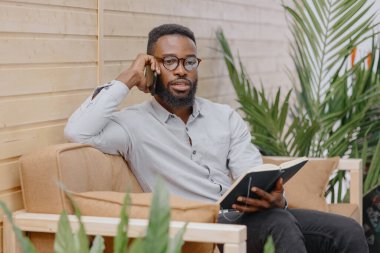 Ofiste çalışan ya da telefonda konuşan ve not defterine not alan Afro-Amerikan. 