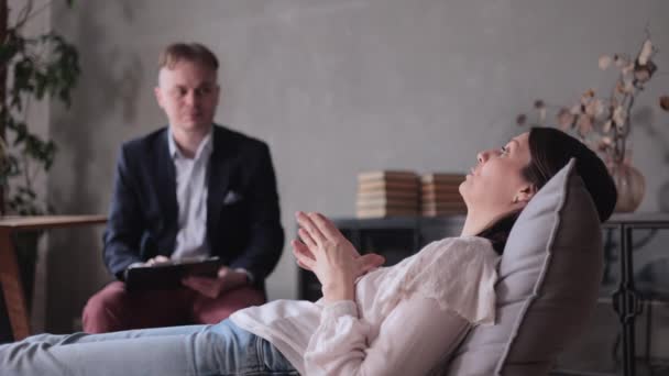 Mužský psycholog vede pacientovu schůzku ve své kanceláři. žena řekne terapeutovi o svých záchvatech paniky — Stock video