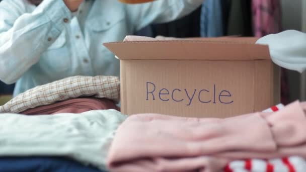 Жінка збирає одяг у коробці для переробки або утилізації.європейська жінка сортує пластик та сміття екологічно чистий спосіб життя — стокове відео