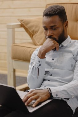 Ofiste çalışan yakışıklı ve genç bir Afrikalı Amerikalı ya da laptopla çalışan bir adam.