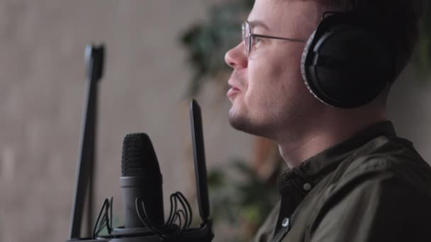 Un animateur de radio ou un baladeur masculin parle dans un microphone avec écouteurs crée du contenu audio en studio ou à la radio sur les ondes. — Video