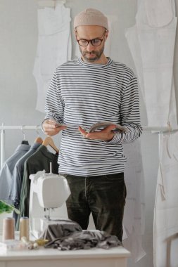 Erkek moda tasarımcısı veya moda tasarımcısı bir dergiye göz atar ve bir müşteriyle telefonda konuşur. Yetişkin bir iş adamı ofisinde çalışıyor.