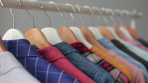Baju menggantung di lemari pakaian atau di butik. Wanita berwarna atau pria berayun-ayun pakaian dengan lancar pada gantungan. lemari pakaian untuk pertemuan bisnis atau tanggal. — Stok Video