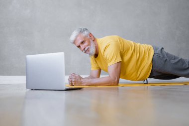 Adamın biri, spor salonunda dizüstü bilgisayarından antrenörle yoga ve fitness yapıyor. İnternetteki son sınıf erkek spor koçu.