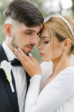 Sokakta kamera karşısında poz verirken şefkatle kucaklaşan gözleri kapalı muhteşem bir düğün çifti. Yeni aile kavramı, aşk ve ilişki.