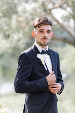 Parkta duran yaka çiçekli gülen damat.