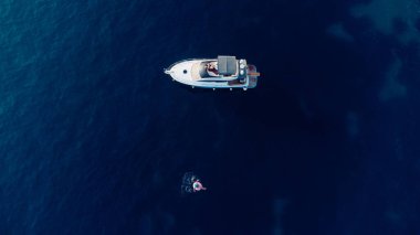 Adriyatik Denizi 'nde yatın yanındaki mavi denizde yüzen ince kadının havadan görünüşü. Kızla yaz deniz manzarası, güzel dalgalar, güneşli bir günde mavi su. İHA 'dan üst görünüm