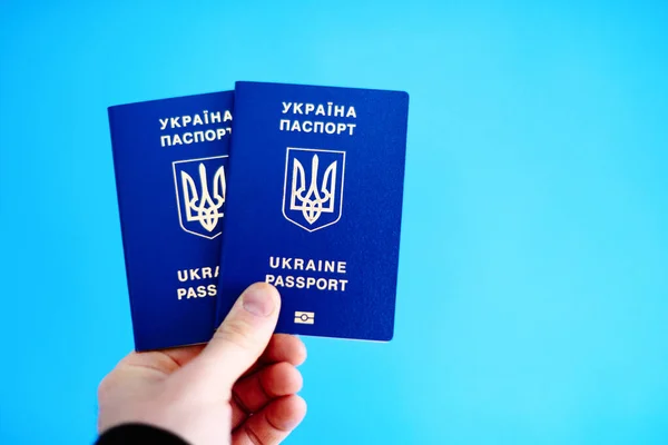 隔離された青の背景にウクライナの2つのパスポートを保持している人の手の画像 青い背景に隔離された男性の手の保持パスポート — ストック写真