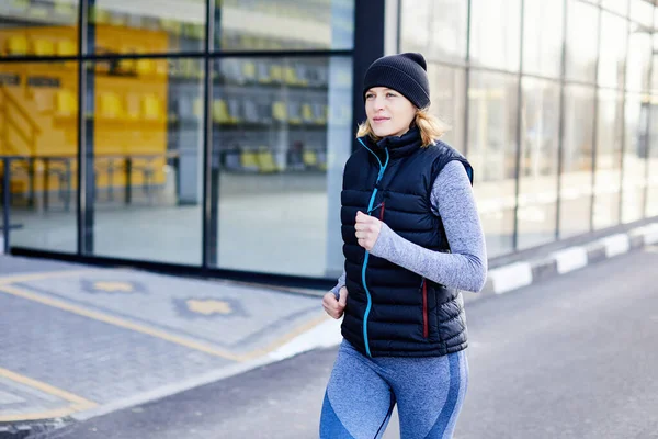 Genç ince bir kız baharın başlarında parkta koşar. Spor kulübünün yakınında koşan çekici bir kadın.