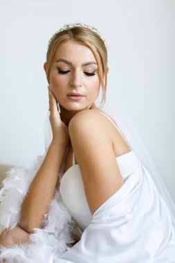 Gelinin beyaz cüppeli sabahı ve odada bir duvak.