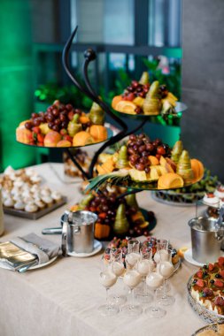 Düğün için. Çikolata. Açık büfe masasında bardaklar, içecekler, meyveler ve farklı tatlılar var..