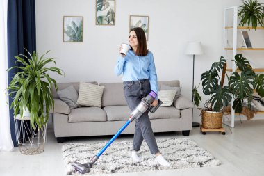 Elektrikli süpürgeyle kahve içen kadın.