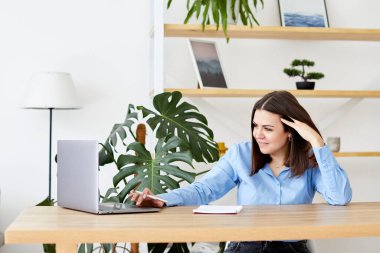 Laptop ekranına bakan neşeli genç bir kadın, evdeki iyi haberler için heyecanlanıyor..