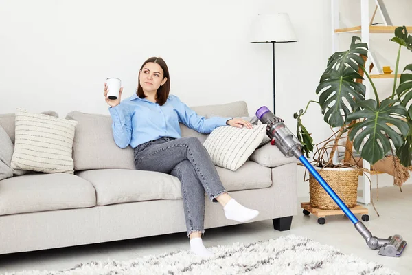 Büyüleyici esmer ev hanımı modern süpürgeyle halıyı temizledikten sonra evde eğleniyor.