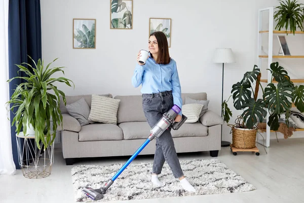 Elektrikli süpürgeyle kahve içen kadın.