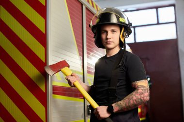 İtfaiyeci kasklı ve baltayla itfaiye arabasının karşısında.. 