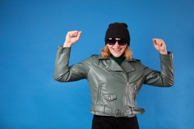 Neşeli ve mutlu genç kadın yalnız dans ediyor, günün tadını çıkarıyor, mavi ceketli, neşeli yüzlü bir kadın eğleniyor.