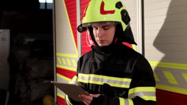 Portrait of firefighter, fireman in protective clothing and helmet using tablet in action fighting