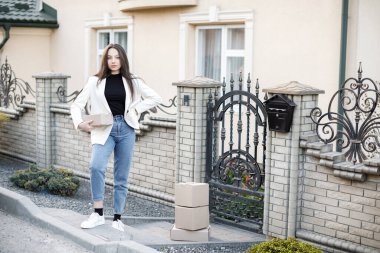 Elinde bir yığın karton kutuyla eve paket taşıyan genç bir kadın..