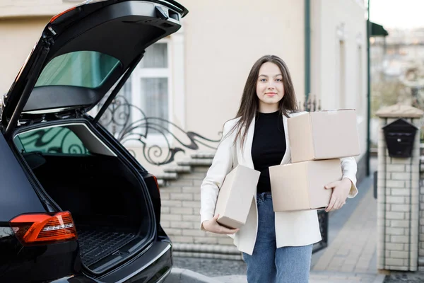 Genç bir iş kadını bir araba bagajından paketler alıyor, arabayla eve geliyor.