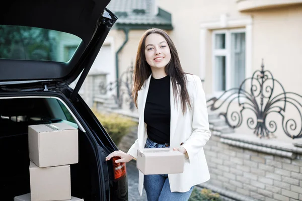 Genç bir iş kadını bir araba bagajından paketler alıyor, arabayla eve geliyor..