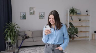 Smiling woman talking on the phone at home near the sofa. Feminine gossip on the smartphone.