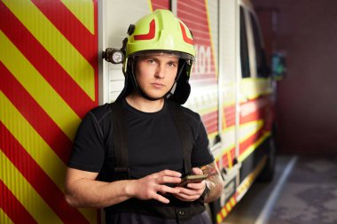 İtfaiye arabasının önünde duran bir itfaiyecinin portresi.