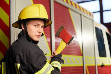 İtfaiyeci arka planında kaskı ve baltası var.. 
