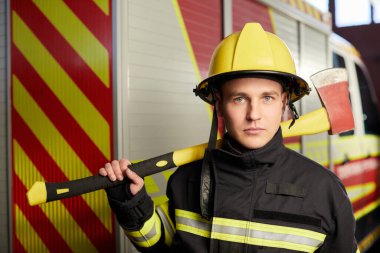 İtfaiyeci arka planında kaskı ve baltası var.. 