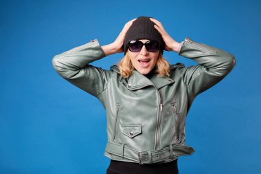 Genç çılgın ve şok olmuş bir kadın saçlarını parmaklarıyla tuttu, şaşkınlıktan ağzı açıldı, mavi üzerine izole bir şekilde.