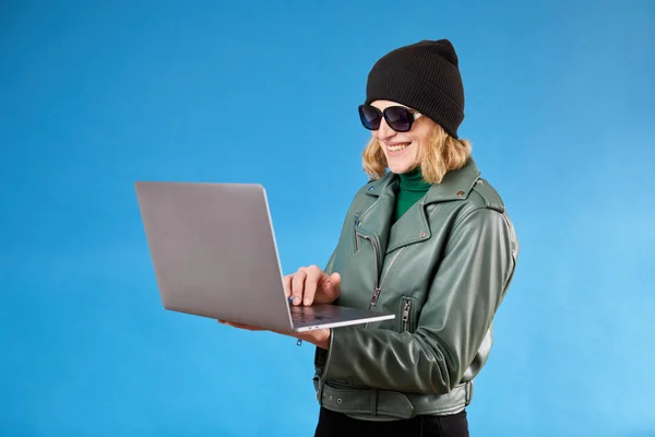 Attractive woman working on new post for her job on laptop, looking at camera with happy inspired smile, watching inspiring video on internet.