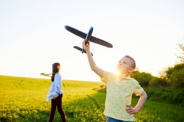 Koşan çocuk ve kız ellerinde iki sarı ve mavi uçak oyuncağı yaz güneşli bir günde tarlada