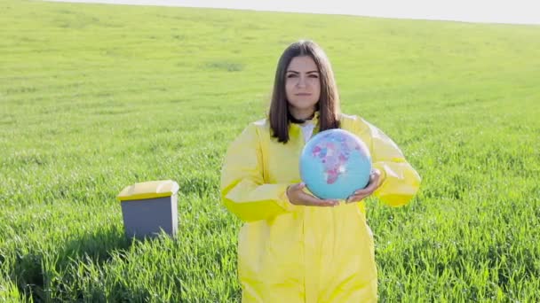 Žena Žlutém Ochranném Obleku Stojí Uprostřed Zeleného Pole Drží Glóbus — Stock video