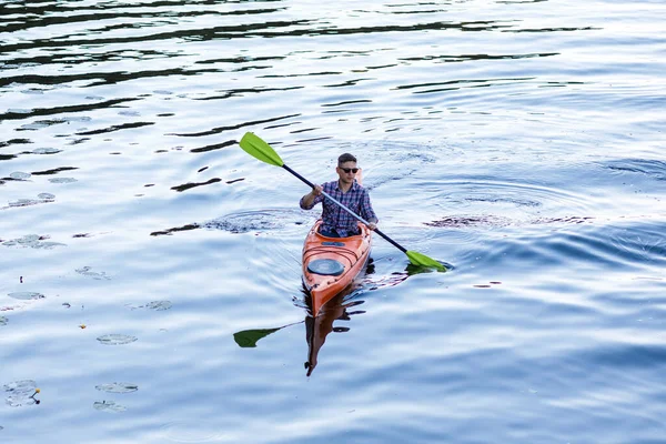 在河里划船 一个年轻的白人男子坐在皮划艇上划桨 水娱乐的概念 — 图库照片