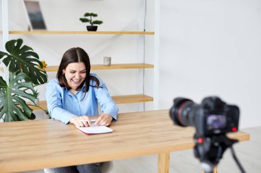 Beautiful Female Sitting at a Desk in a Cozy Living Room and Following a Video School Lesson on Laptop Computer. Student Studying Remotely. Chat with Friends on Social Network.