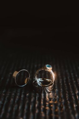 Wedding rings on an old wooden surface, rustic style. Close-up of two gold wedding rings and engagement ring for a wedding.