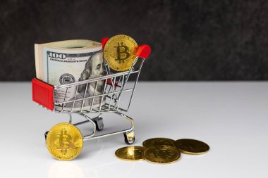 Bitcoin and roll of dollars in shopping cart or basket on dark grey background. Buy or Sell. The concept of the impact of virtual currency on the economy.