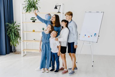 Telefonla selfie çekiyorum. Okulda öğretmenle birlikte bir grup çocuk öğrenci..